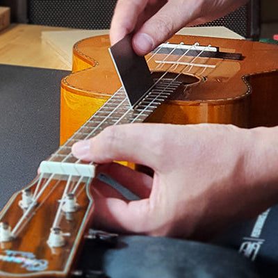 Bei einer Ukulele wird die Saitenlage gecheckt