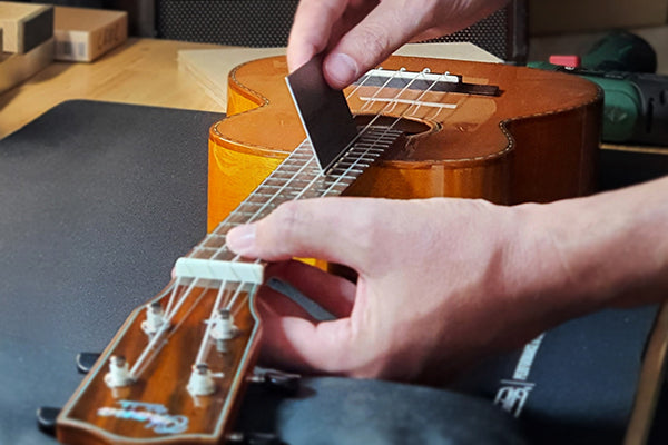 Bei einer Ukulele wird die Saitenlage gecheckt