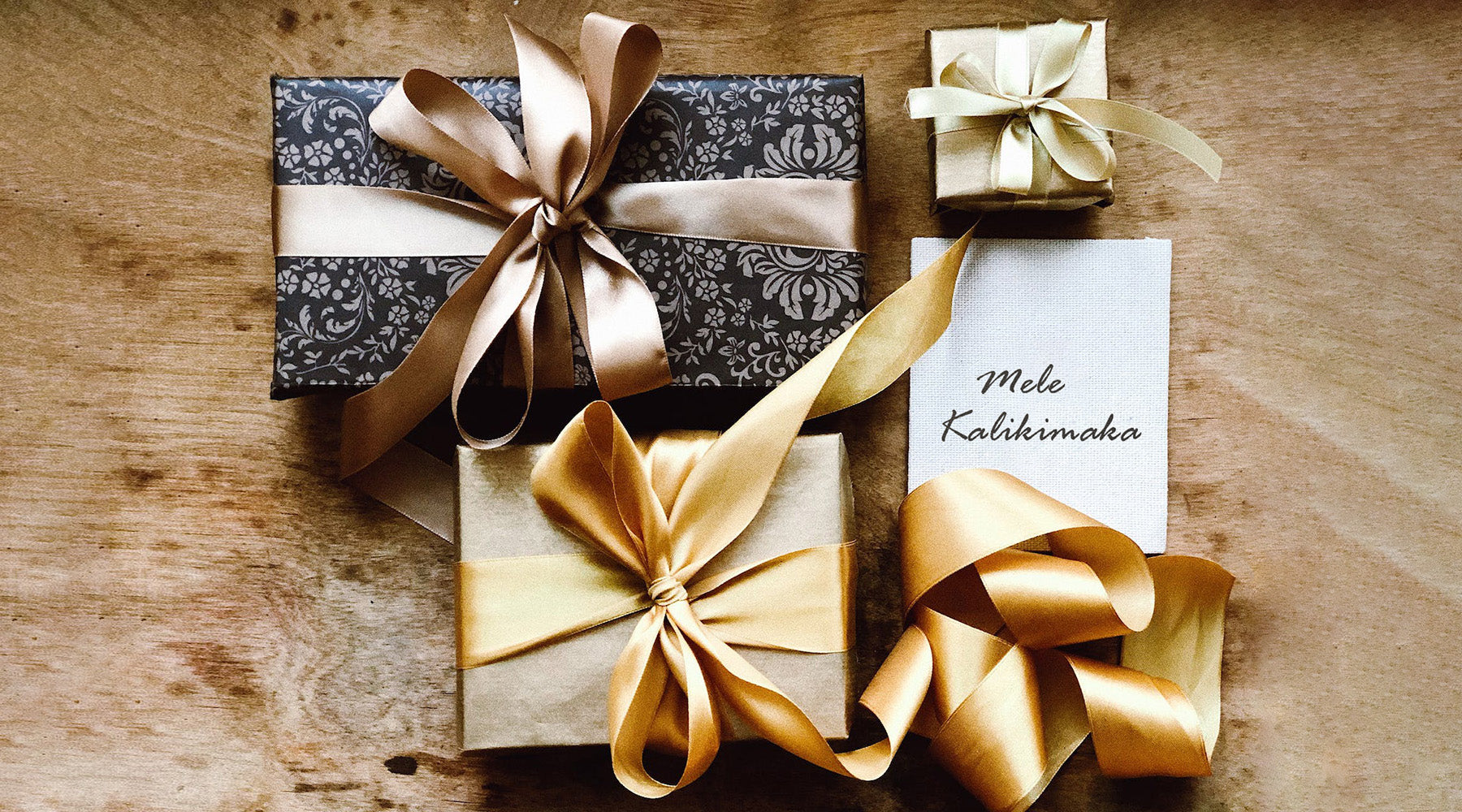 Elegant verpackte Geschenkboxen und eine Karte mit Mele Kalikimaka