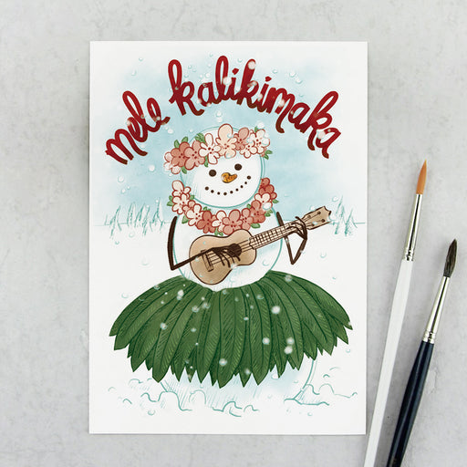 Weihnachtskarte mit Ukulele-spielender Schneefigur im Palmenblattrock, darüber der Schriftzug Mele Kalikimaka 